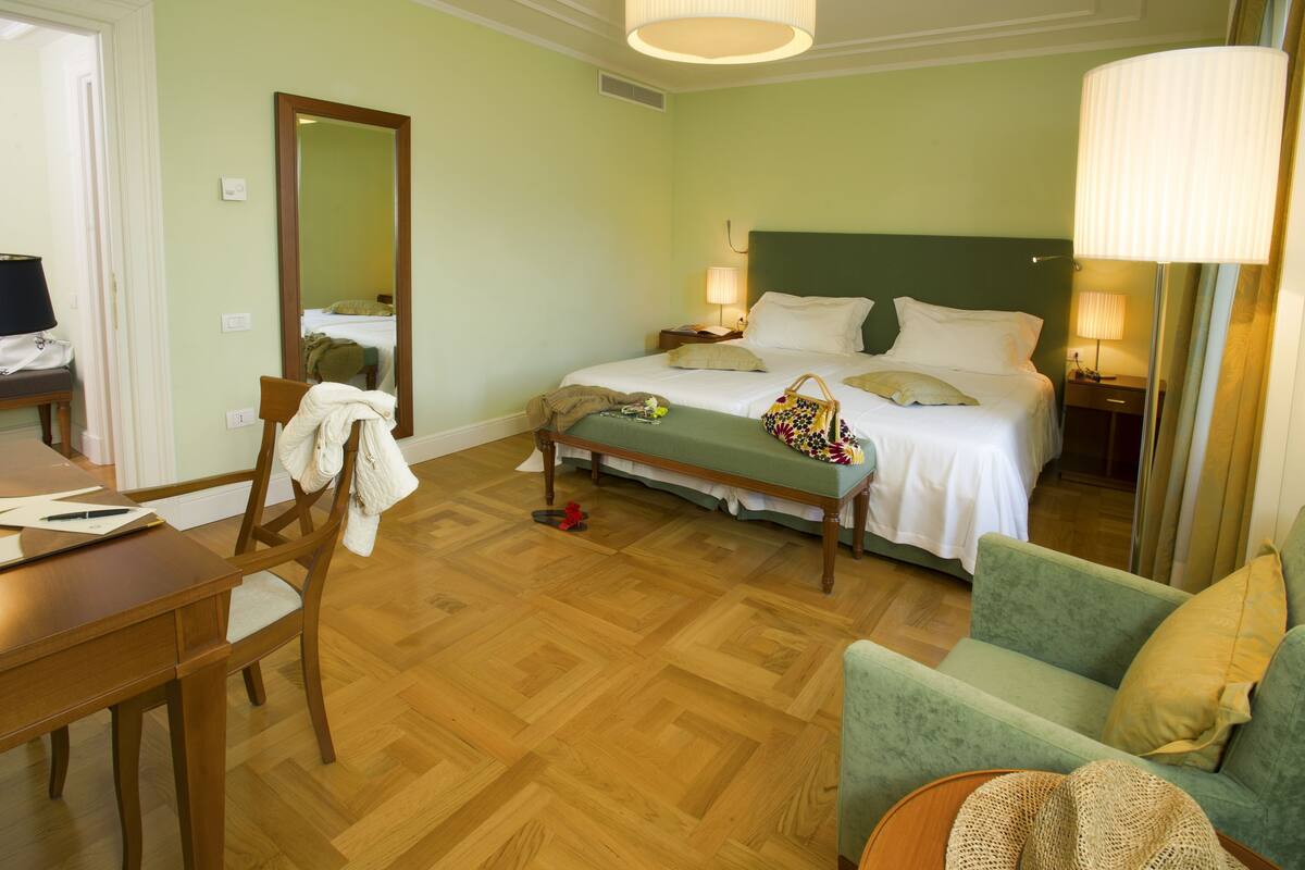 A hotel room with a bed, a desk, a chair, and a sofa.