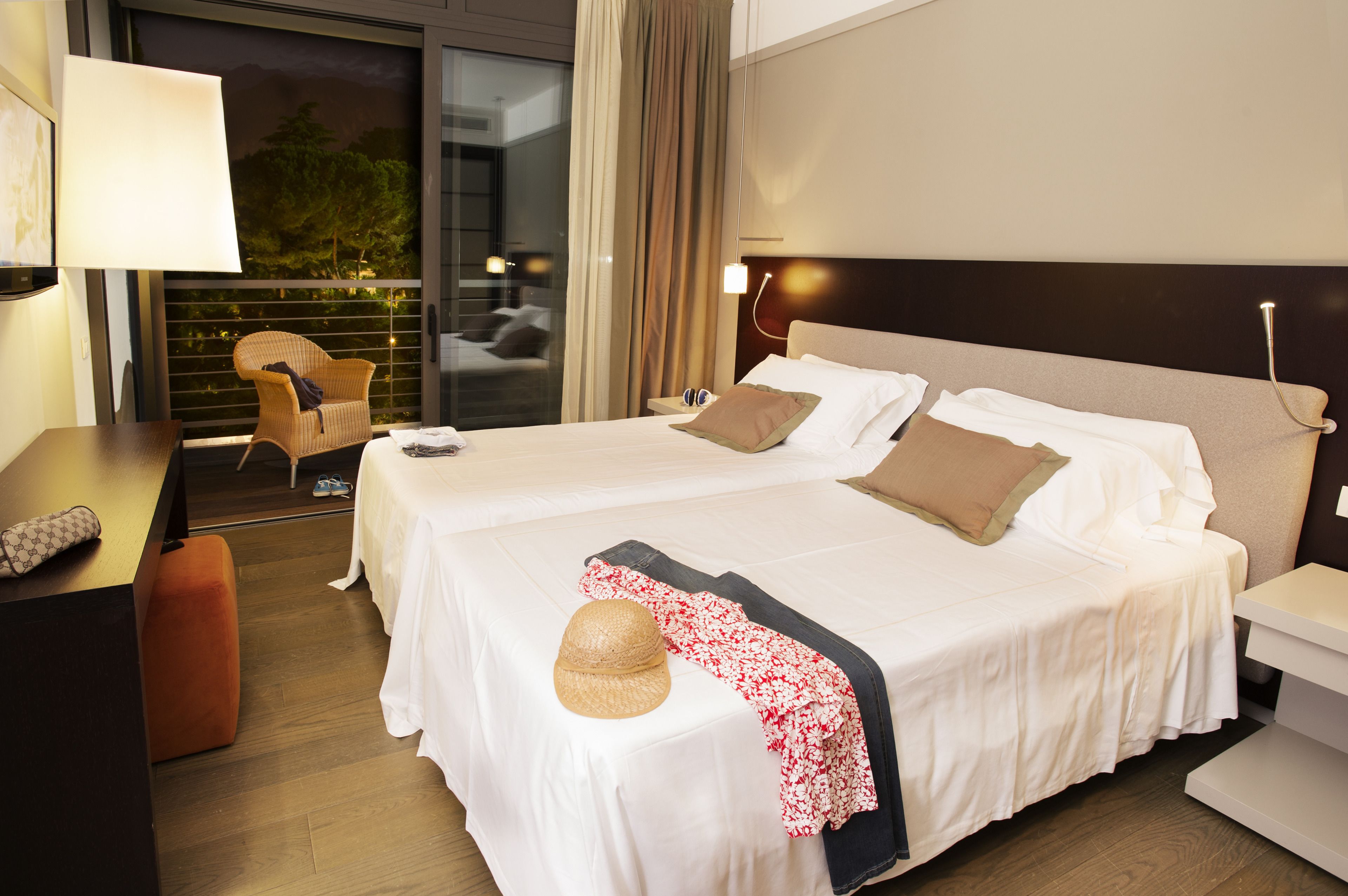 Une chambre d’hôtel avec deux lits, un bureau, une chaise et une vue sur l’extérieur.
