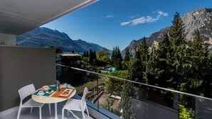 Un balcón con una mesa lista para el desayuno, con vistas a un paisaje montañoso y una zona de piscina.