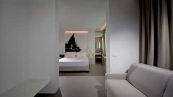 Habitación de hotel moderna con cama, sofá, baño y vistas a la ciudad.