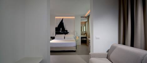 A modern hotel room with a bed, a sofa, a bathroom, and a view of the cityscape.