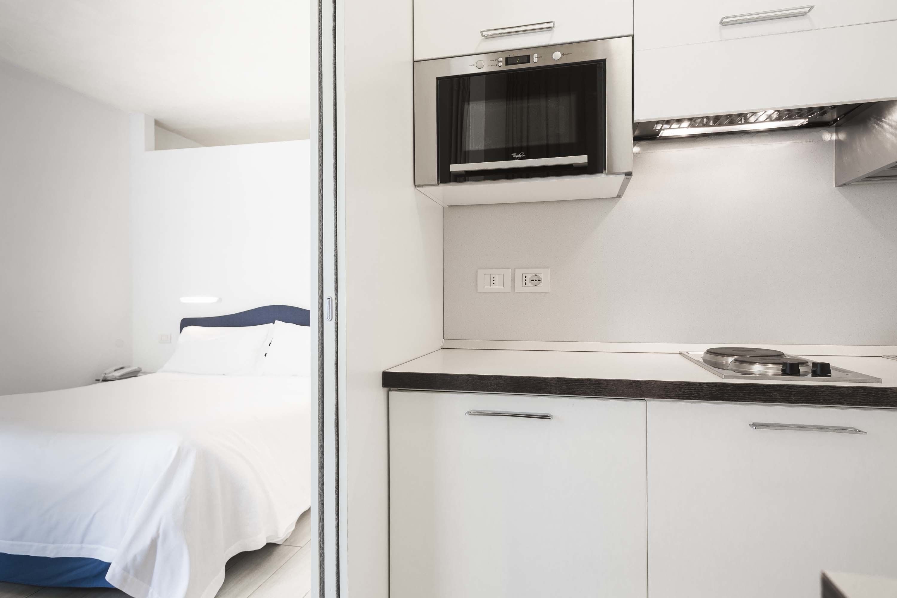 A compact kitchenette with a microwave, a small stove, and a countertop.