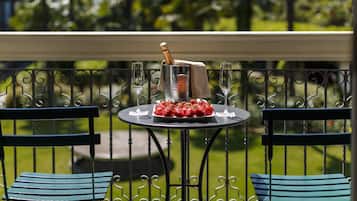 Un tavolo con una bottiglia di champagne, bicchieri e un piatto di fragole su un balcone con ringhiere in metallo e sedie.