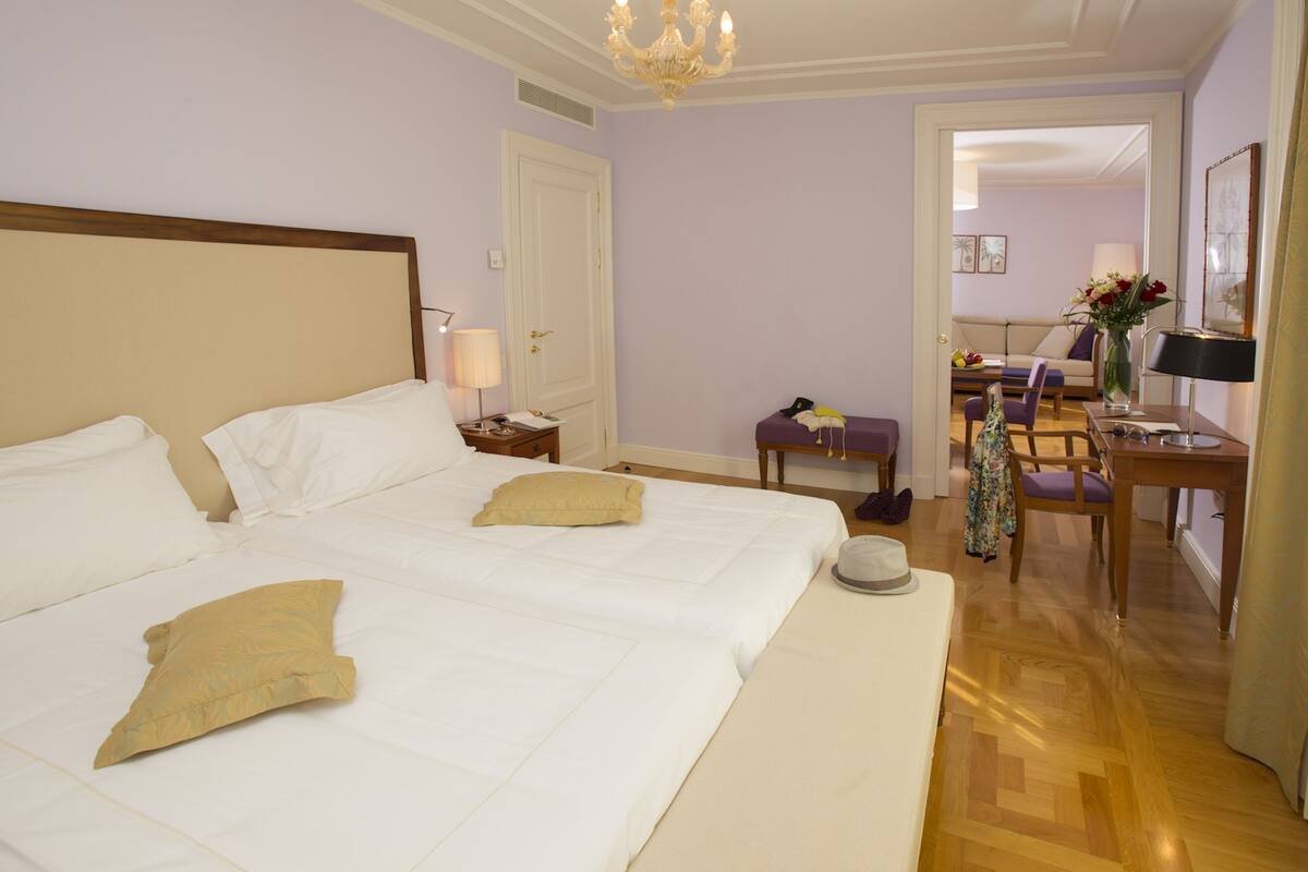 A hotel room with a large bed, a desk, and a chair.