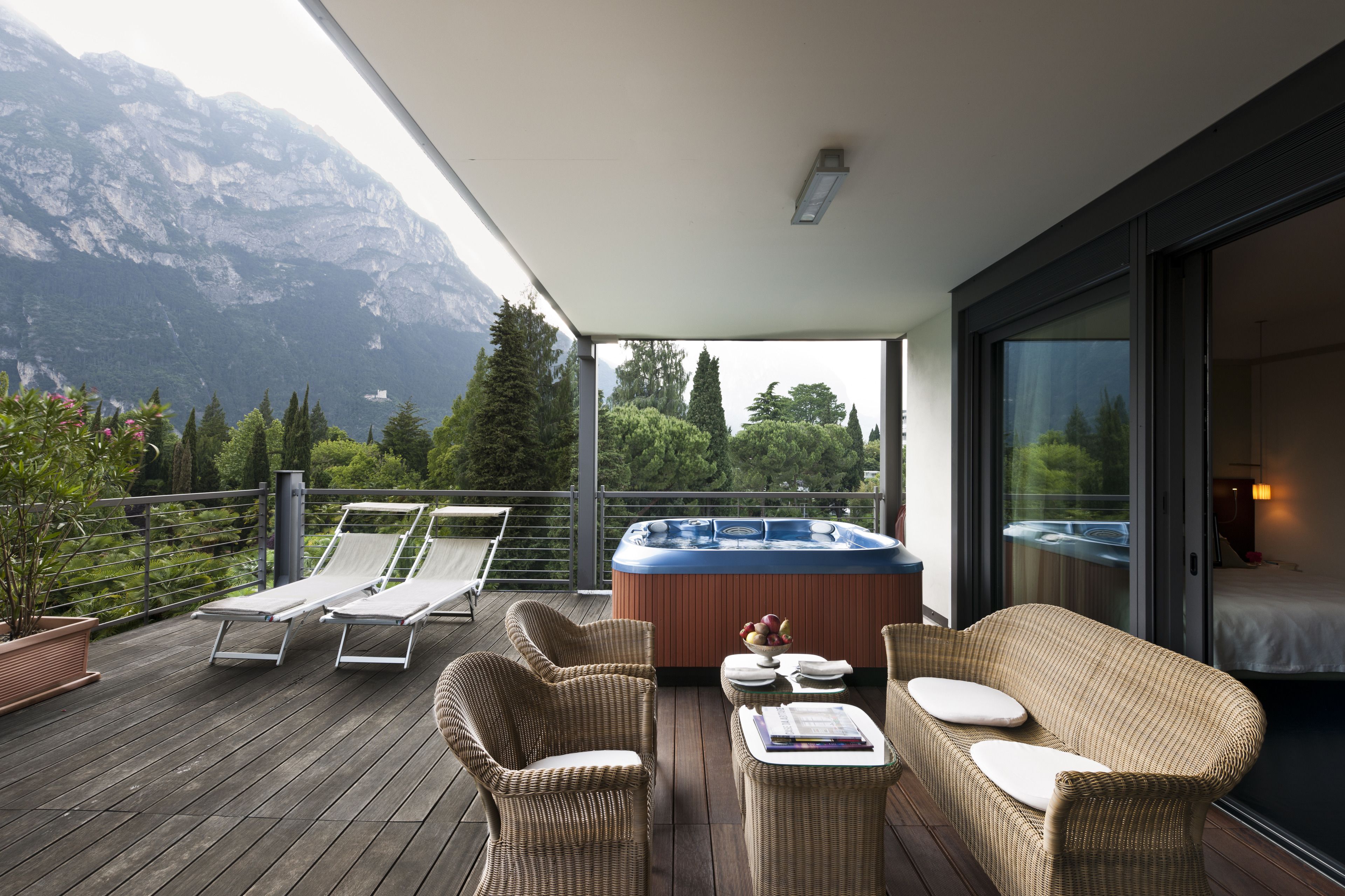 Ein Balkon mit Korbmöbeln, einem Whirlpool und Blick auf die Berge.