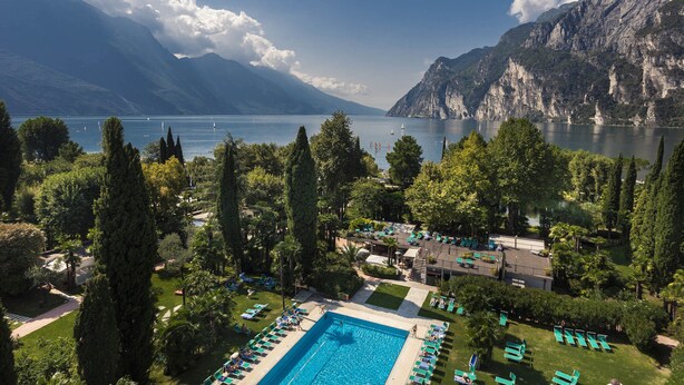 Un resort con piscina, sillas de descanso y vistas a un lago y montañas.