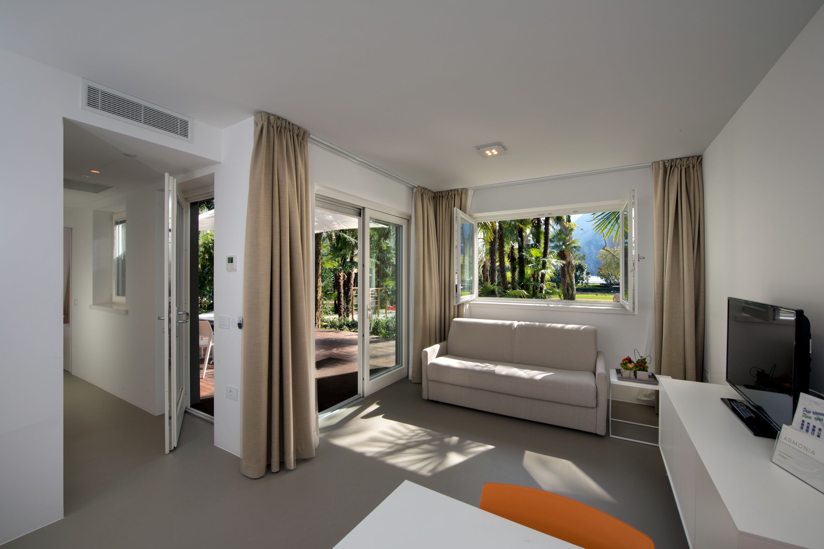 Quarto de hotel moderno com sofá, televisão e escrivaninha.