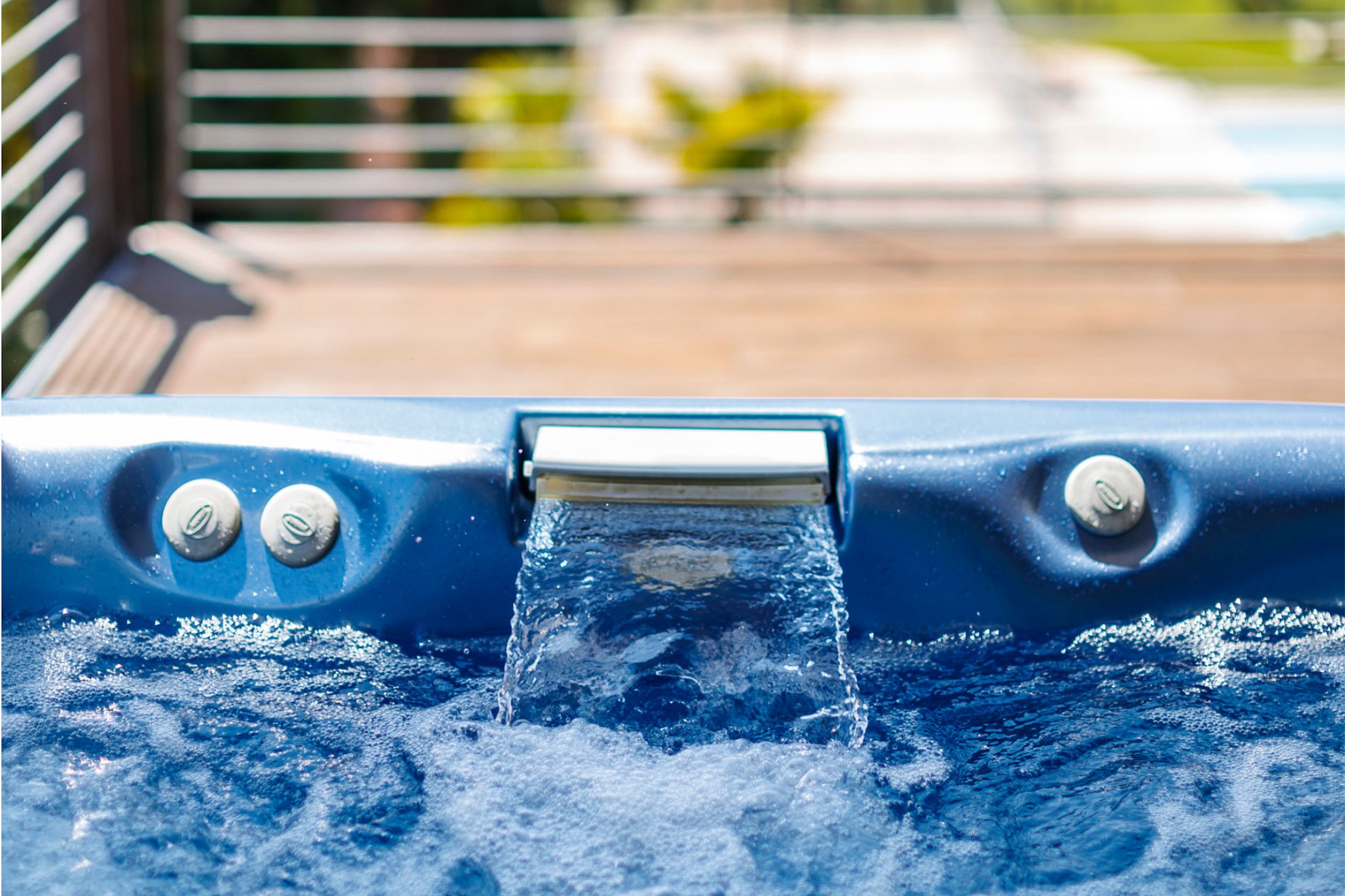 Un jacuzzi con agua fluyendo por un caño central, rodeado por una terraza de madera.