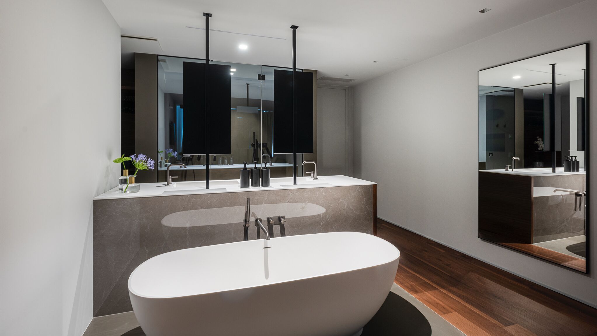 A modern bathroom with a freestanding bathtub, a large mirror, and a vanity with a sink.