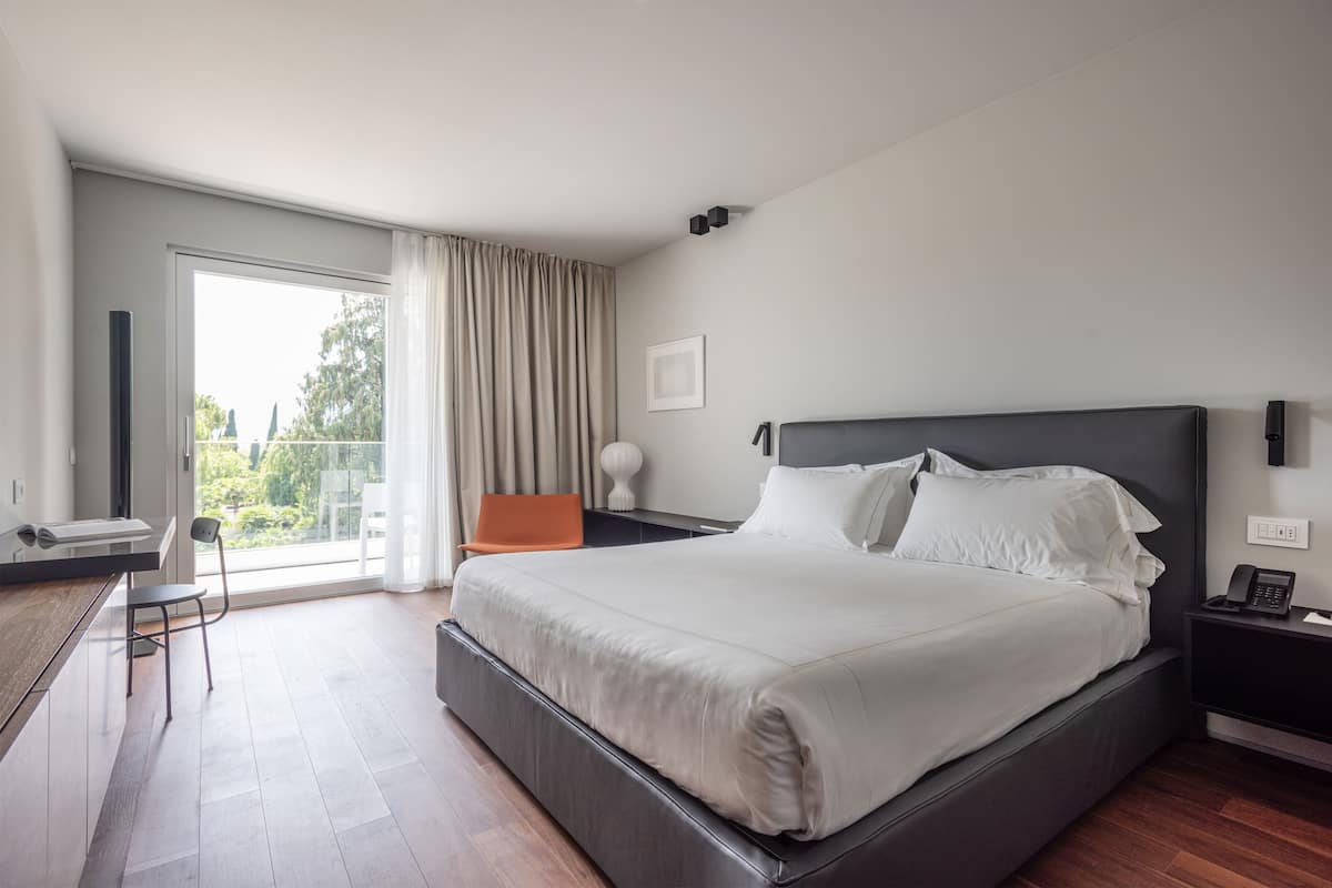 A modern hotel room with a large bed, a desk, and a chair.