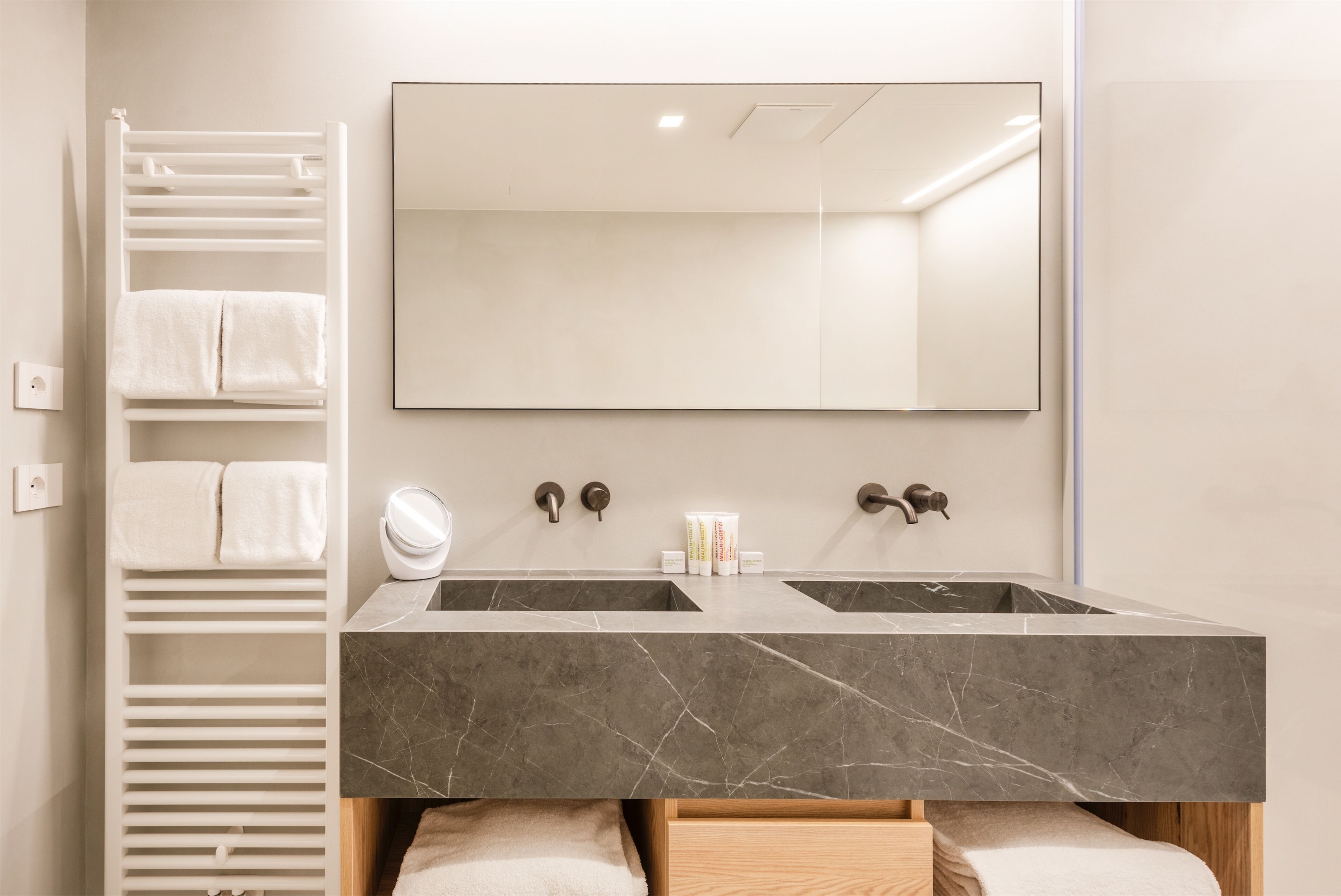 A bathroom with two sinks, a towel rack, and a mirror.