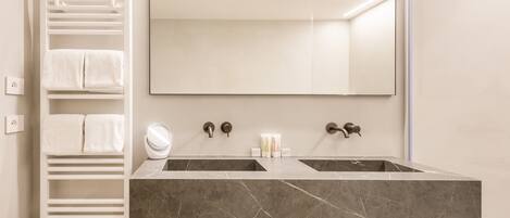 A bathroom with two sinks, a towel rack, and a mirror.