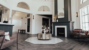 A spacious lobby with a round wooden coffee table, a fireplace, and a large mirror.