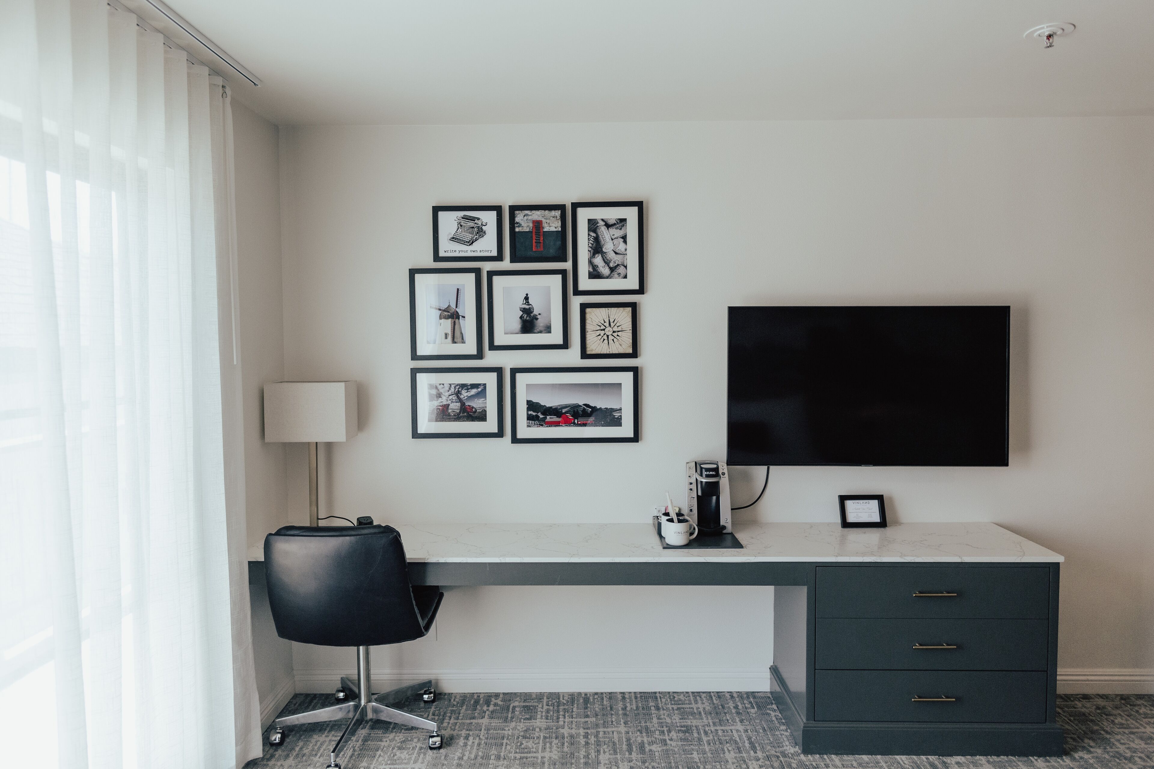 Habitación de hotel con escritorio, silla y televisor de pantalla plana montado en la pared.