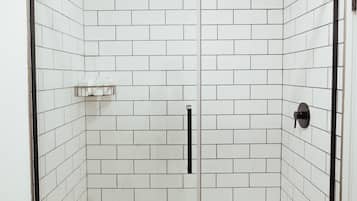 A modern shower with white tiles and a glass door.