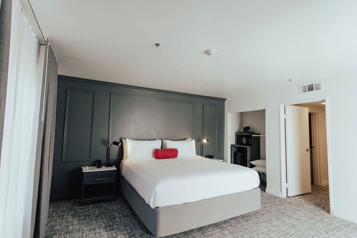 Une chambre d’hôtel avec un grand lit, une table de chevet, un bureau et une armoire.