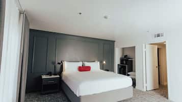 Une chambre d’hôtel avec un grand lit, une table de chevet, un bureau et une armoire.