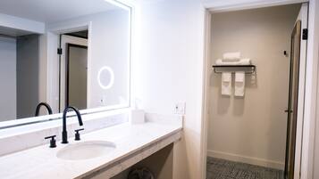 A bathroom with a white marble sink, black faucets, a large mirror, and a towel rack.