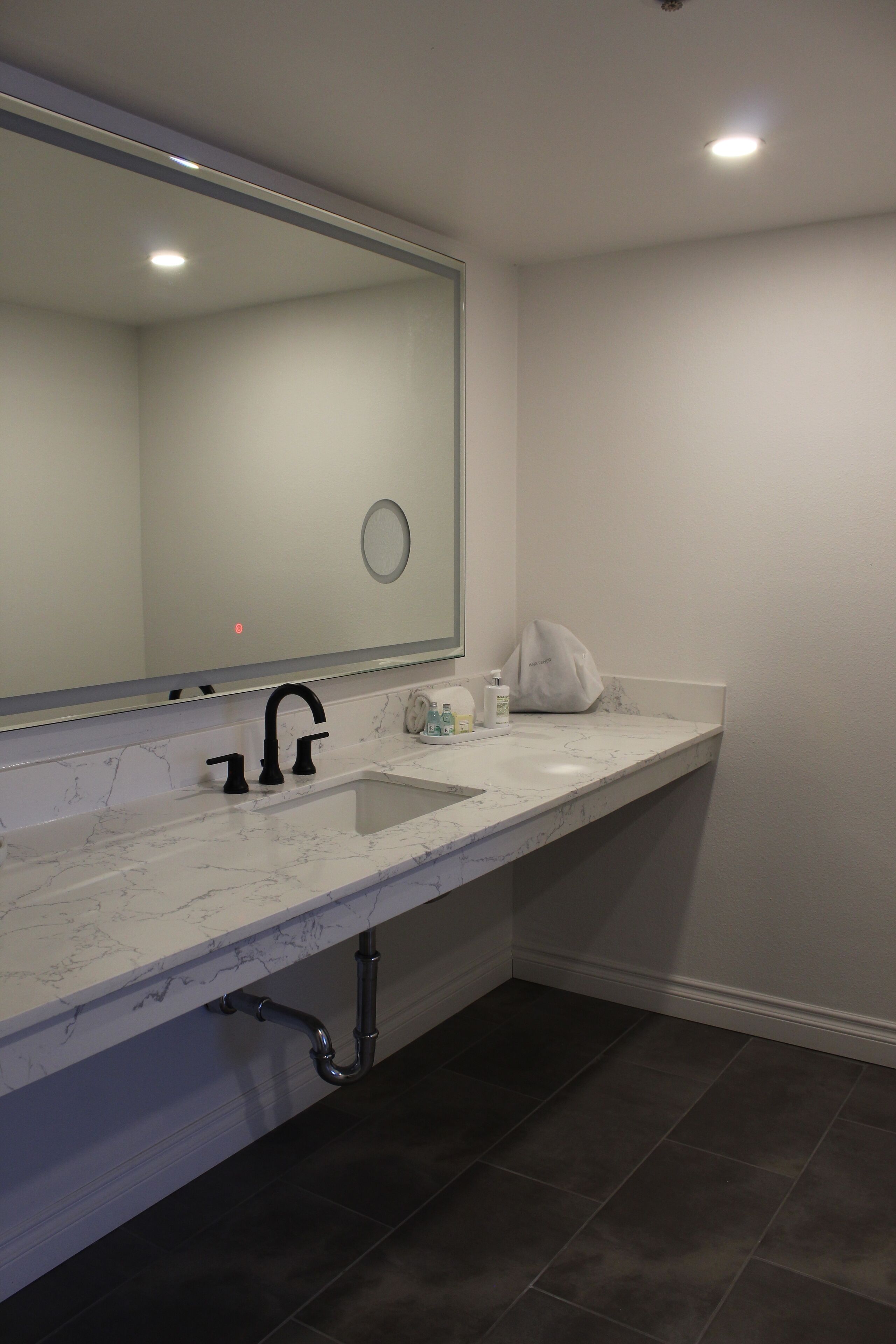 Un baño moderno con un espejo grande, un lavabo de mármol blanco y un perchero para toallas.