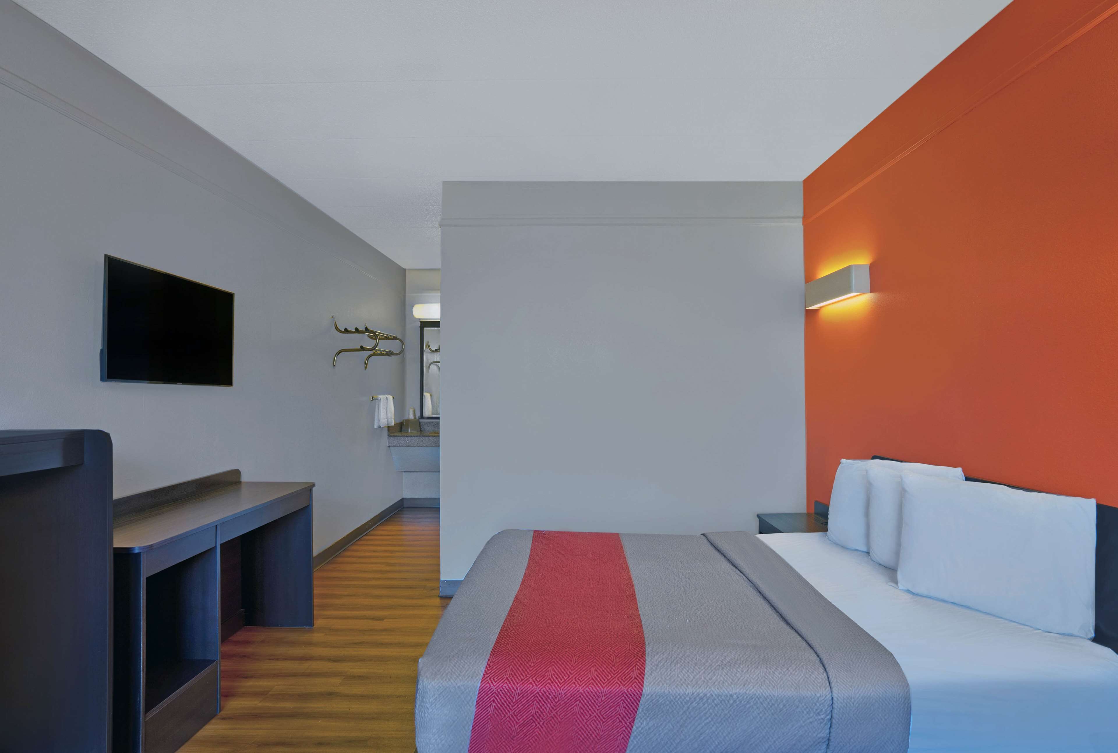 Una habitación de hotel moderna con una cama, un escritorio y un televisor.