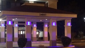 Entrada de hotel con una zona cubierta, número 24057, y pilares iluminados.