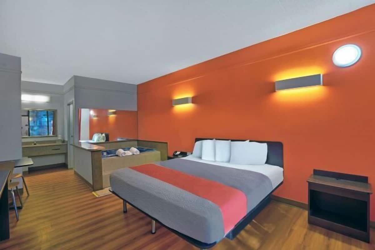 A hotel room with a bed, a desk, a chair, a small table, and a window.