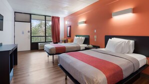Habitación de hotel con dos camas, un escritorio y una ventana con cortinas.