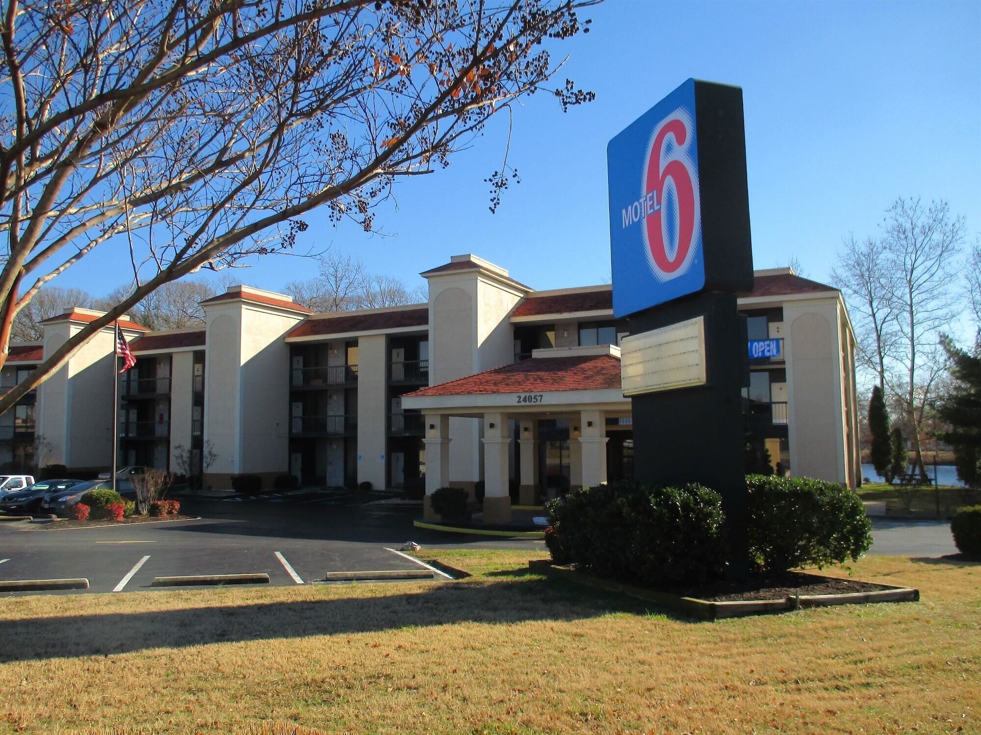 A Motel 6 building with a red roof, multiple balconies, and a parking lot in front.