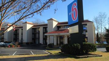 A Motel 6 building with a red roof, multiple balconies, and a parking lot in front.