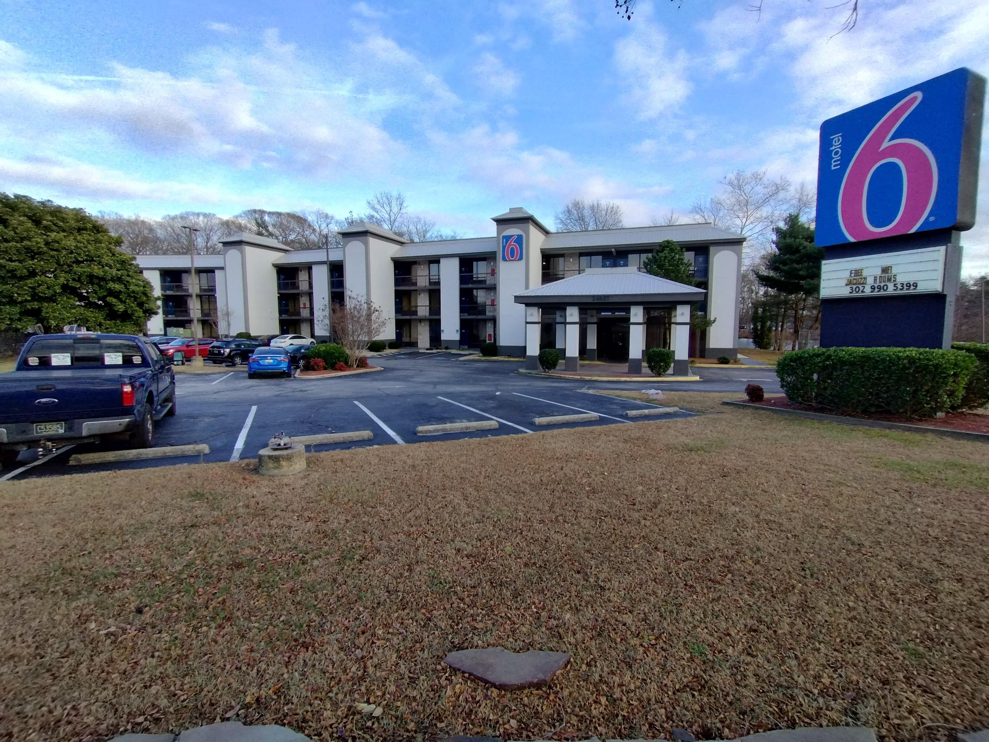 Un motel con un grande cartello, un parcheggio e un edificio su più piani.
