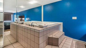 A modern bathroom with a large mirror, a bathtub, and a sink. - Econo Lodge Inn & Suites Virginia Beach - Norfolk (Virginia Beach)