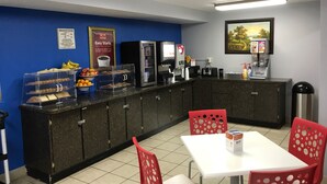 A breakfast area with a counter, a coffee machine, a toaster, and a refrigerator. There are red chairs and a white table. - Econo Lodge Inn & Suites Virginia Beach - Norfolk (Virginia Beach)