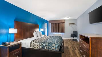 A hotel room with a large bed, a desk, a chair, and a TV.