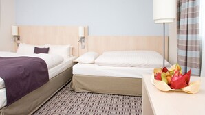 Una habitación de hotel con dos camas, una mesita de noche con lámpara y un arreglo floral sobre la mesa.