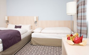 Una habitación de hotel con dos camas, una mesita de noche con lámpara y un arreglo floral sobre la mesa.