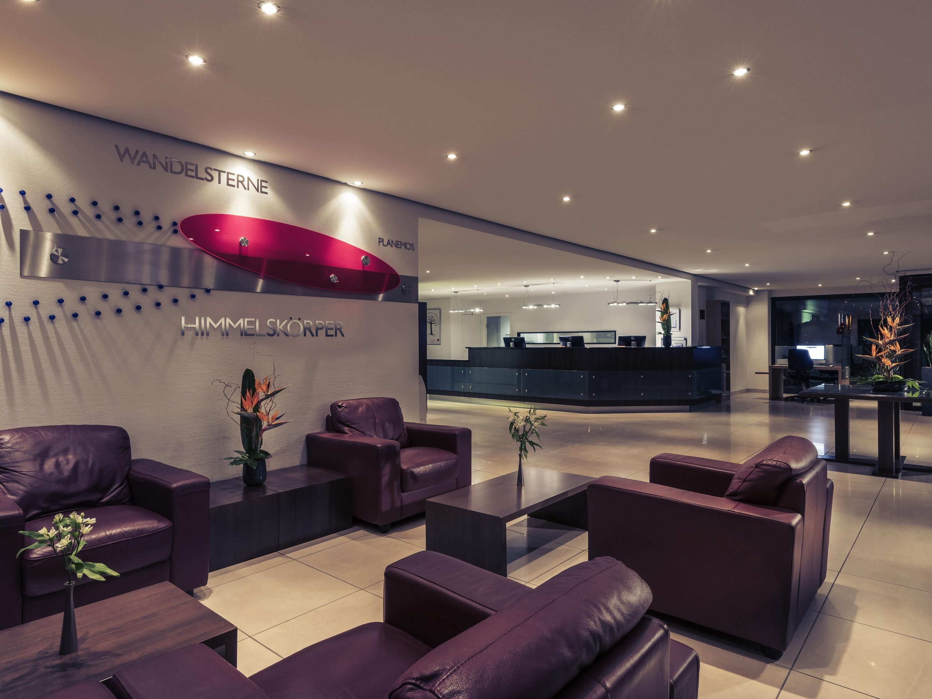 A modern lobby with leather seating, a reception desk, and a large red accent wall.