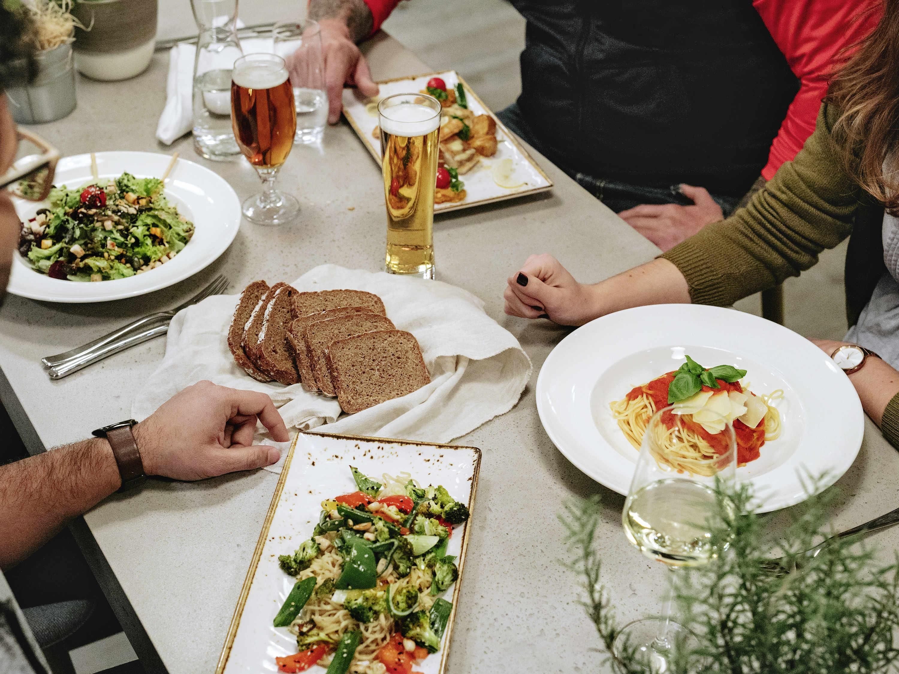 Una mesa de comedor con diversos platos, como pasta, pan y una ensalada.