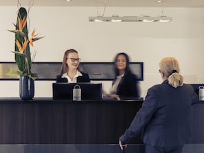 Un taulell de recepció amb una planta en test i una làmpada moderna penjant a dalt.