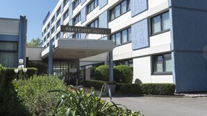 Un hotel moderno con un letrero que dice "Mercure HOTEL" y un acceso cubierto.