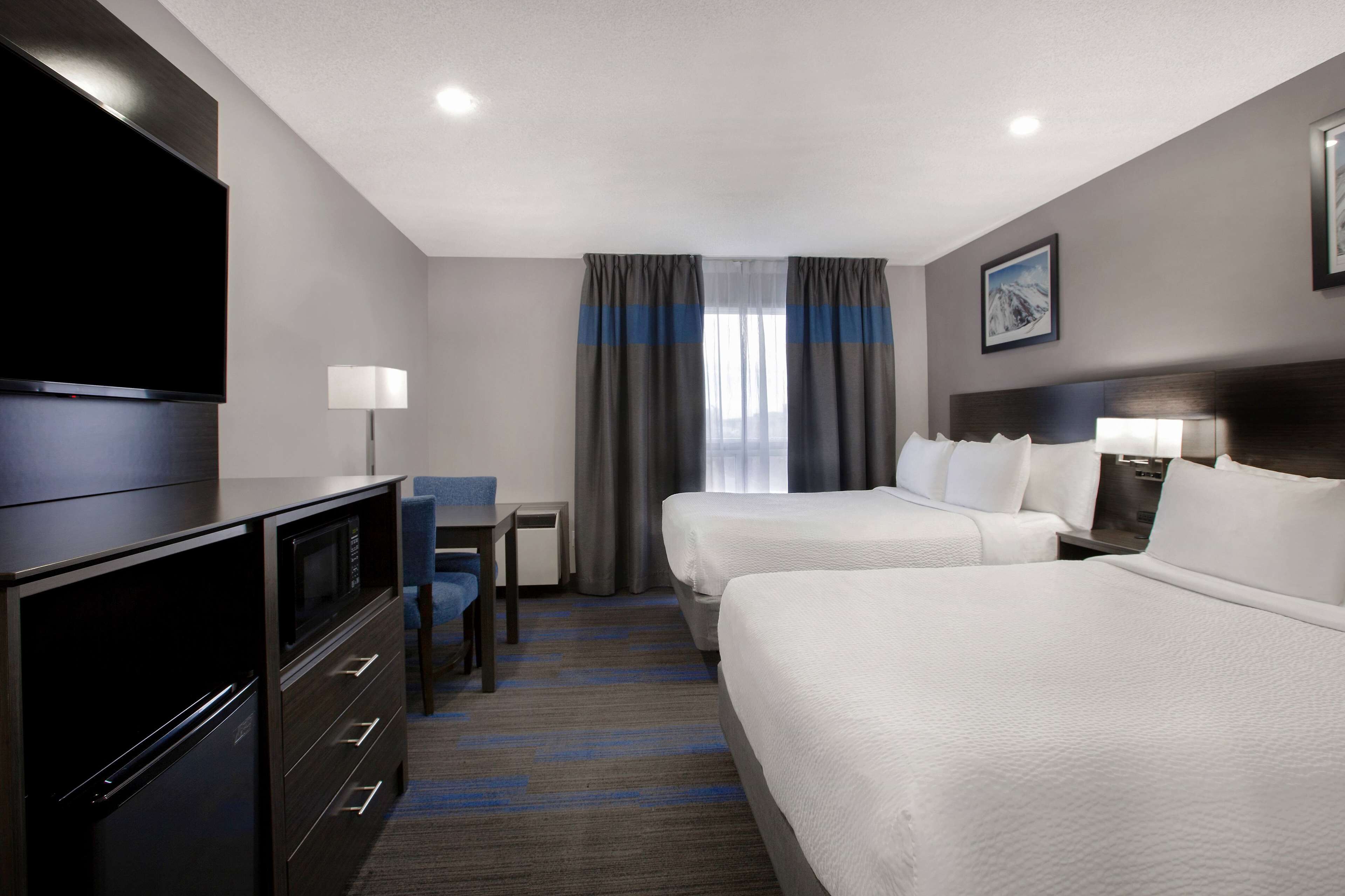 A hotel room with two beds, a flat-screen TV, a desk, and a chair.