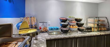 Un buffet proposant une variété de plats, notamment des viandes, des salades et des produits de boulangerie.