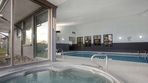 A swimming pool with a hot tub, clear glass walls, and a view of the outdoors.