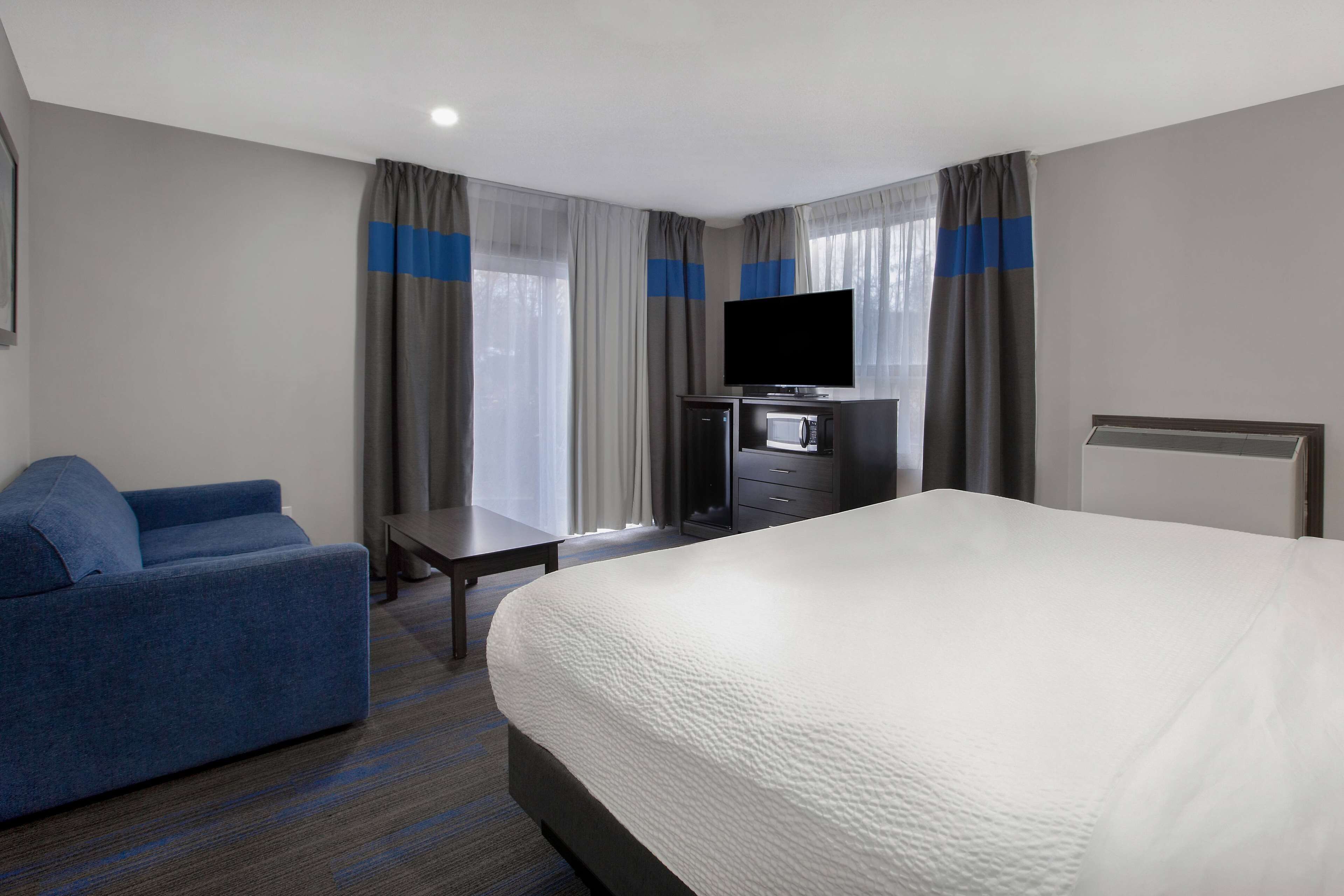 Une chambre d’hôtel équipée d’un lit, d’une télévision, d’un bureau, d’une chaise et d’un four à micro-ondes.