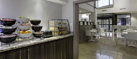 A buffet area with various food items and a seating area with tables and chairs.