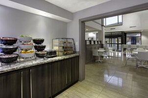 Zona de bufé con diversas opciones de comida y un área de estar con mesas y sillas.