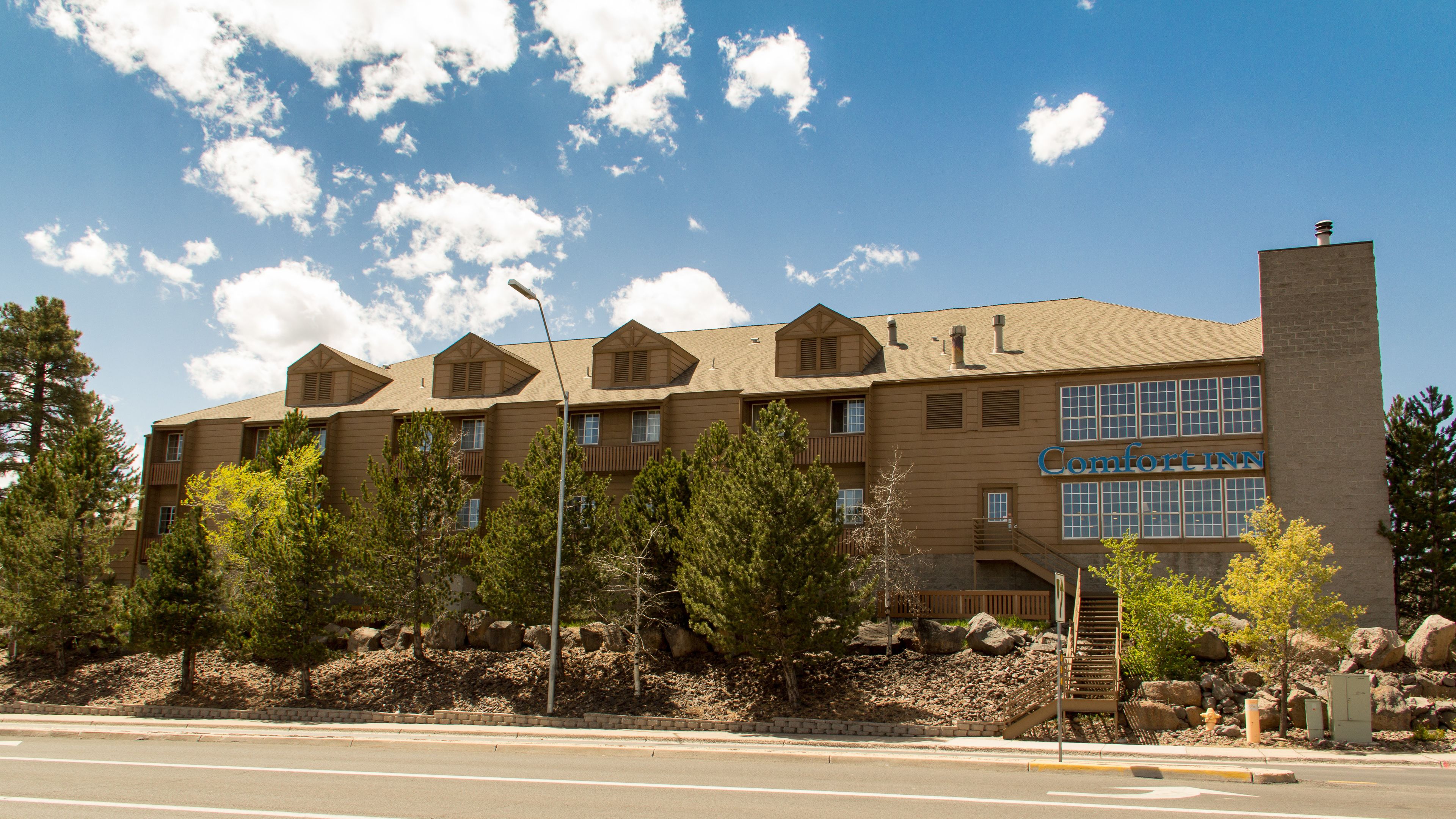 Un immeuble à plusieurs étages, sur lequel on peut lire l’inscription « Comfort Inn ». Il se distingue par sa façade en briques, ses nombreuses fenêtres et sa cheminée.