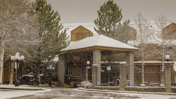 A snow-covered building with a covered entrance, a sign indicating no parking, and a street with snow on the ground.