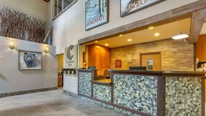 A hotel reception area with a stone wall, wooden reception desk, and a bear painting. - Comfort Inn Flagstaff South I-17 (Flagstaff)