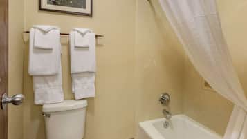 A bathroom with a toilet, two towels hanging on a rack, a bathtub, and a shower curtain.
