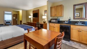 A hotel room with a bed, a wooden desk, a chair, a small kitchenette with a microwave, and a refrigerator. - Comfort Inn Flagstaff South I-17 (Flagstaff)